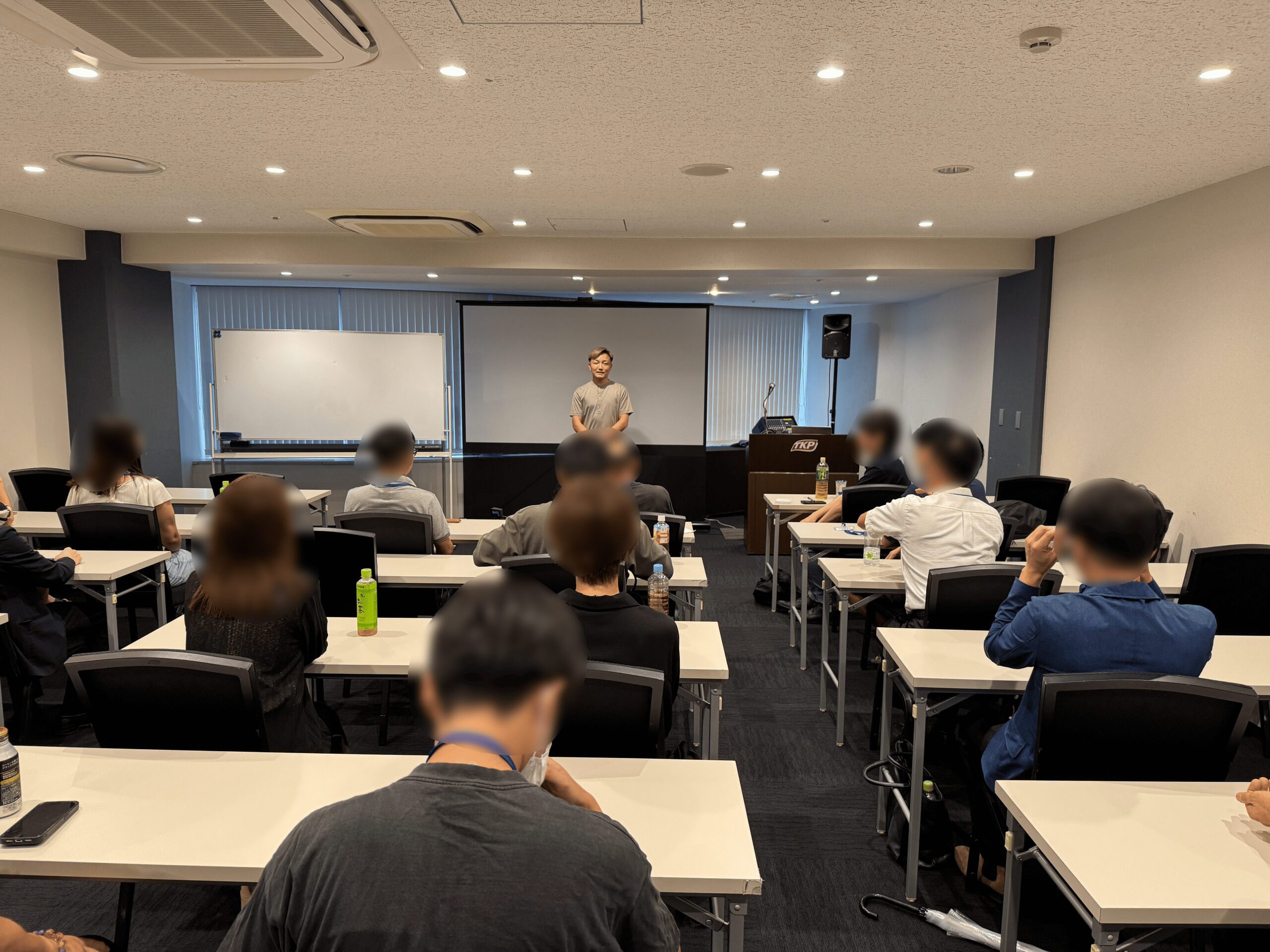 一人の男性が講義室の中で複数の受講者に講義をしている様子